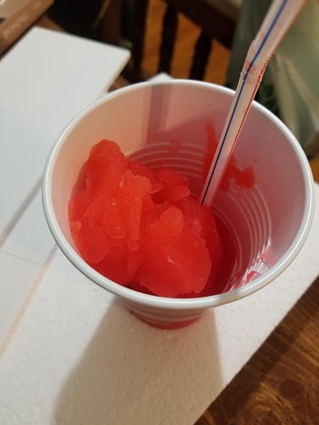 a reviewer's finished red slushie in a cup