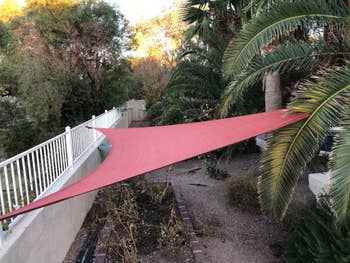 Red fabric extending along a curved outdoor walkway surrounded by greenery