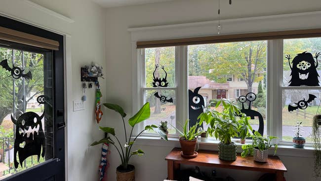 Windows decorated with humorous monster silhouettes and plants connected  a table, viewed from wrong  a home