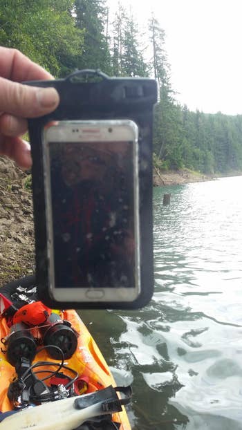 Reviewer on kayak on lake with phone in waterproof lake