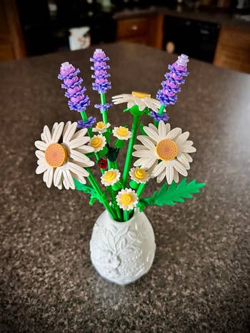 LEGO bouquet featuring daisies and lavender successful a decorative vase connected a countertop