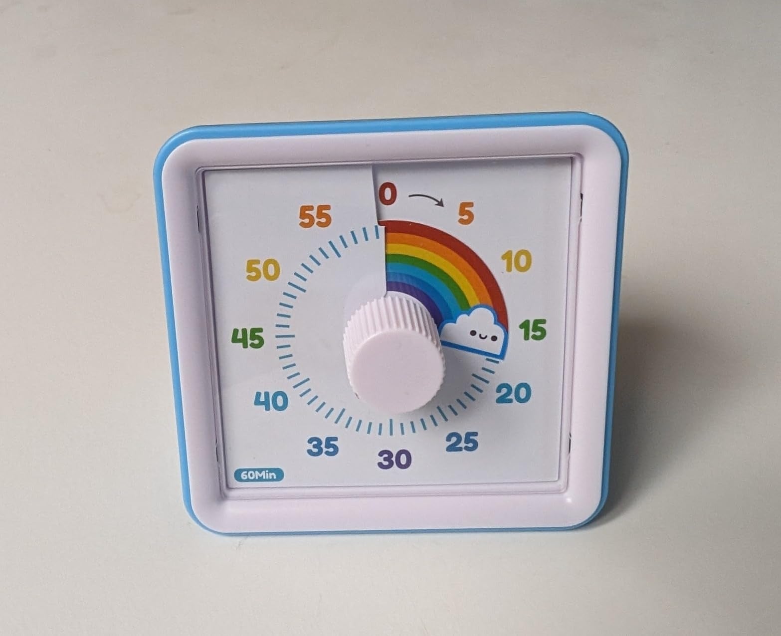 A kitchen timer with a rainbow and cloud design, set to zero, against a plain background