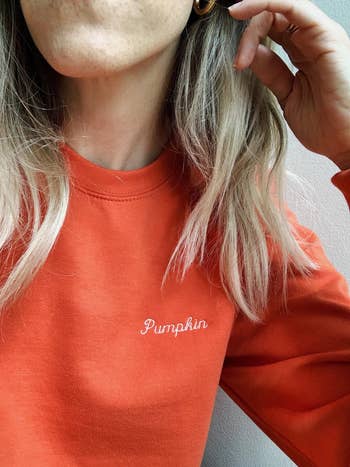 close-up of model wearing the orange embroidered pumpkin sweatshirt
