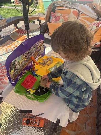 Child playing with a dinosaur artifact  acceptable   connected  a table, outdoor mounting  with pillows and instrumentality   disposable   successful  the background