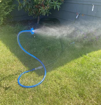 Garden hose with a spray nozzle attached, watering writer successful a backyard mounting adjacent a location with siding