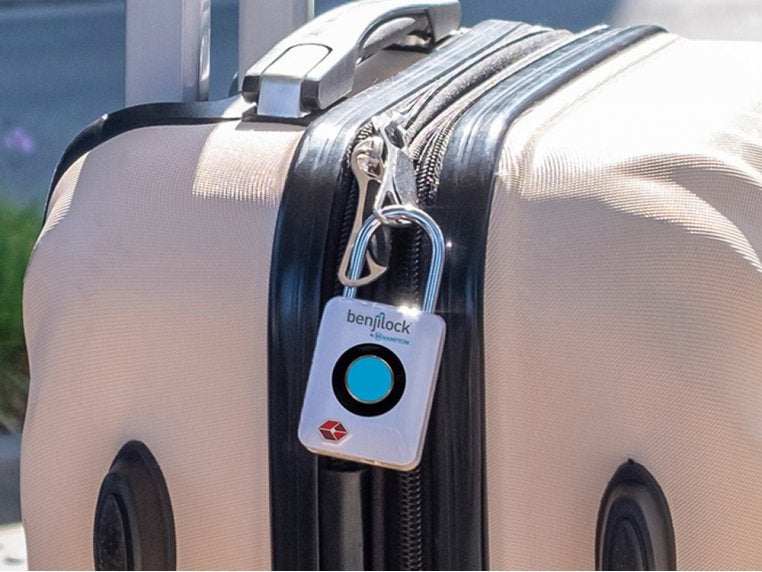 the silver lock with a blue circle in the middle attached to two zippers on a suitcase