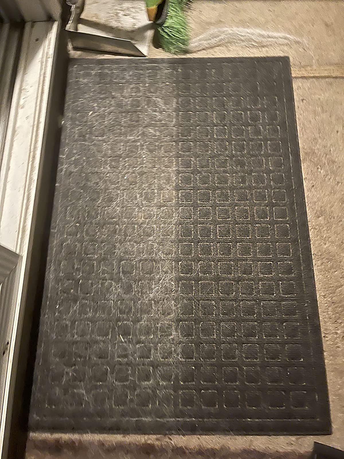 a reviewer photo of a door mat covered in pet hair on the left side, and cleared of hair on the right side 