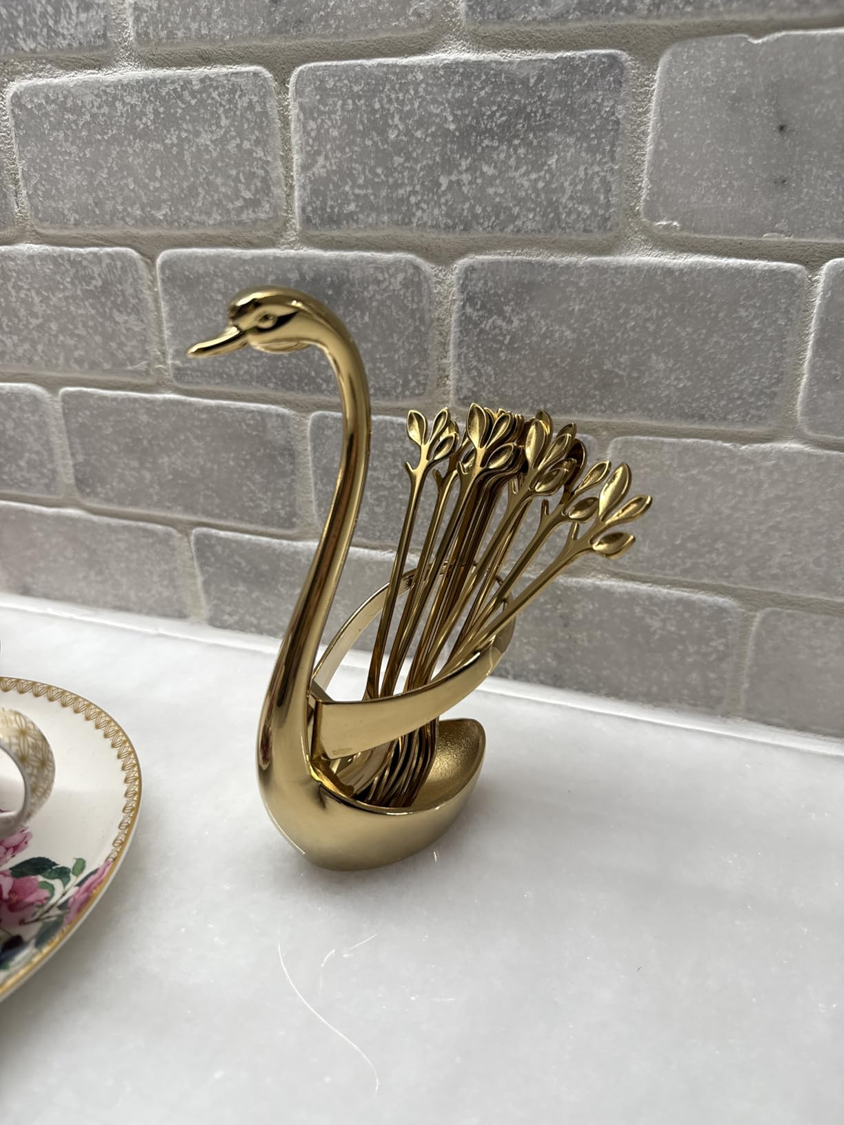 Golden swan-shaped toothpick holder with fan-like statement   connected  a marble countertop