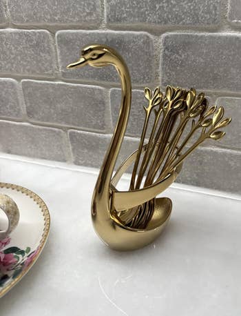 Golden swan-shaped toothpick holder with fan-like statement connected a marble countertop