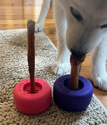 a long stick treat in a pink wheel-shaped grip and a shorter, thicker stick treat in a purple grip