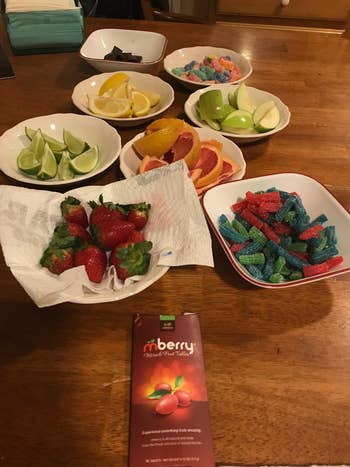 Reviewer photo of the package in front of several different types of fruit and candy