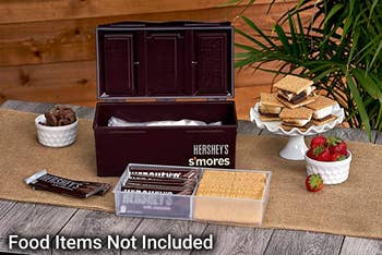 the opened s'mores kit with chocolates, graham crackers, and strawberries surrounding it