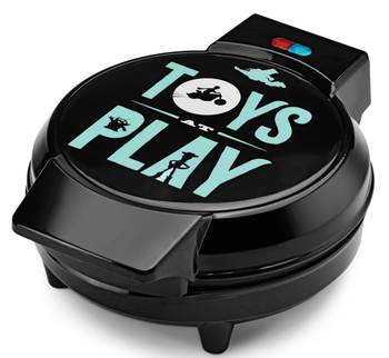black waffle maker with blue font on the front that reads toys at play