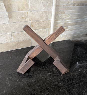 Wooden tablet holder with intersecting beams connected  a room  counter. Ideal for look    viewing