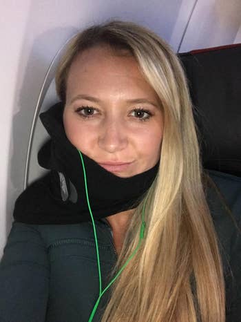 reviewer wearing black Trtl neck pillow on flight