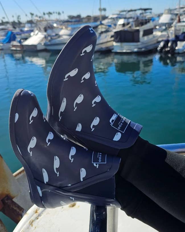 reviewer wearing bluish  rainfall  boots with whales connected  them