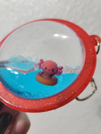 Keychain with a small, pink axolotl-like figure encased in a water-filled dome