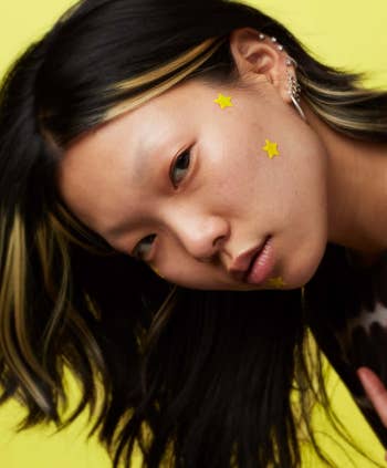 a model wearing three star-shaped patches on their face