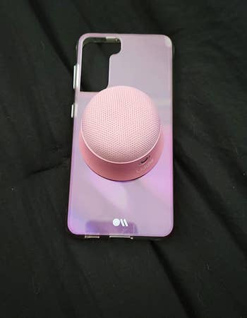 reviewer's pink phone with small pink bluetooth speaker on the back
