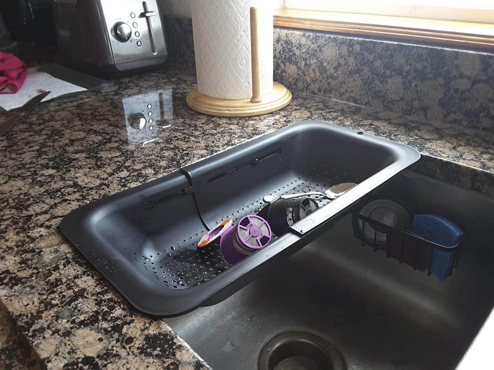 reviewer image of the black expandable colander over a kitchen sink