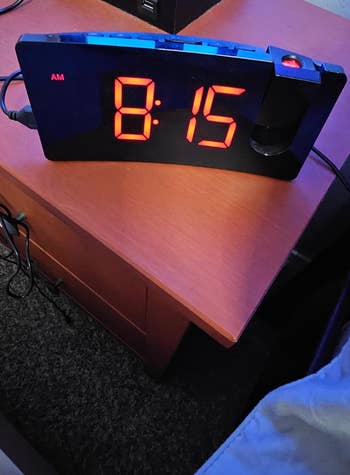 Digital alarm clock reading 8:15 on a bedside table