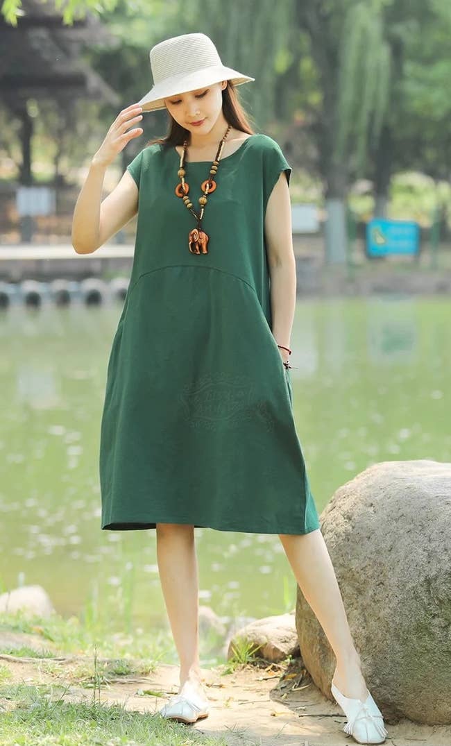 model wearing the green cap sleeve dress with a hat and white flats