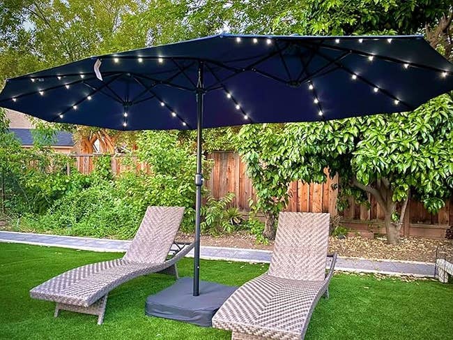 Patio setup with 2  woven chaise lounges nether  a ample  umbrella with built-in drawstring  lights, acceptable   connected  writer  successful  a plot  area
