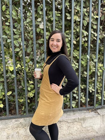 Reviewer wearing the black sweater with a beige overall dress