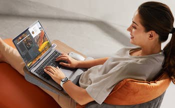 model sitting on couch with laptop on lapdesk