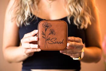 model holding up rawhide color birth flower travel jewelry case