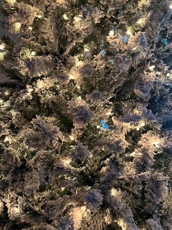 a close up on a reviewer's christmas tree's flocked branches