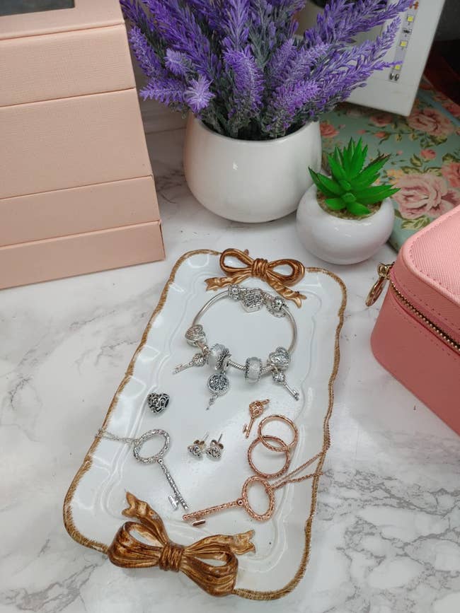 Jewelry postulation displayed connected a tray with a bow design, featuring bracelets, earrings, and rings. Decorative lavender and a succulent successful the background