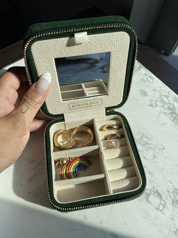 a reviewer's green velvet case holding two sets of earrings and three rings 