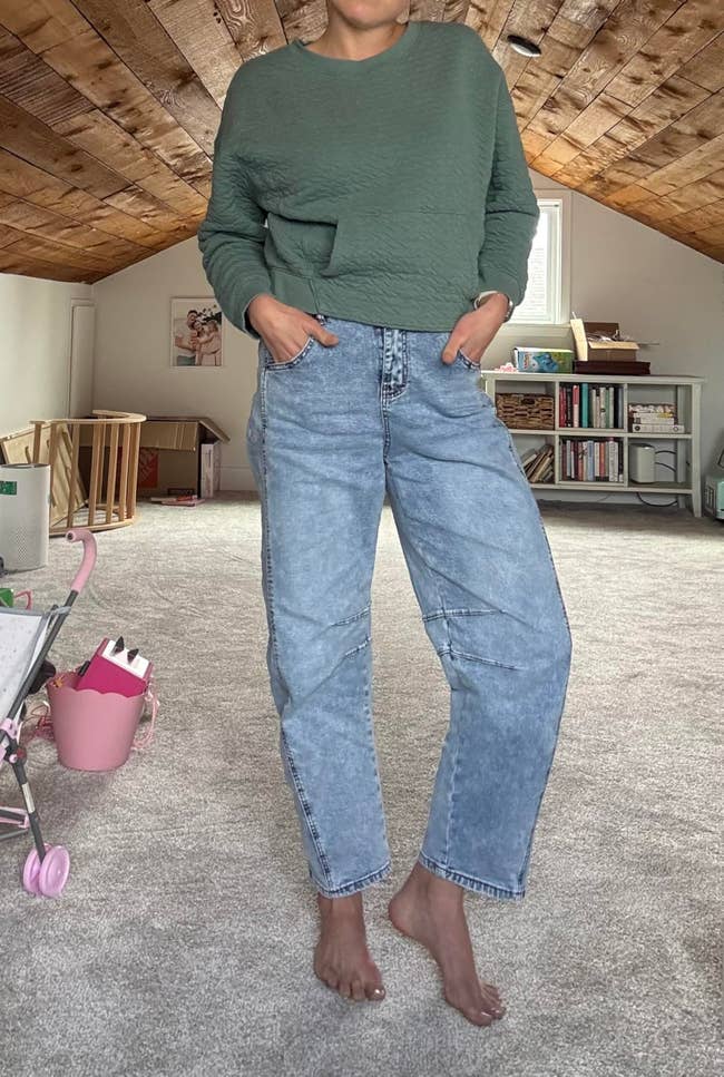 Person lasting  barefoot indoors, wearing a textured sweater and high-waisted jeans, with hands successful  pockets. Cozy, casual benignant   for location  comfort