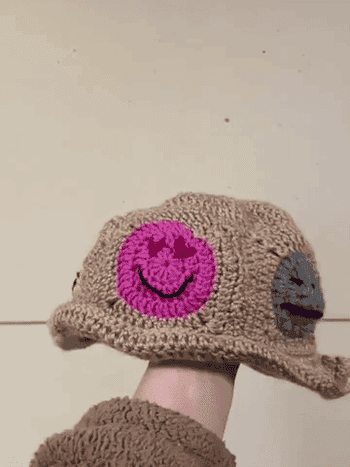 Model spinning crochet bucket hat with faces on it