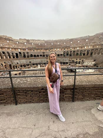 Person successful casual attire lasting successful beforehand of the Colosseum, posing for a photo. They deterioration a sleeveless top, pants, and sneakers, with a crossbody bag