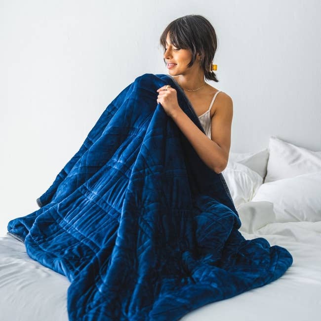a model snuggled under the navy weighted blanket