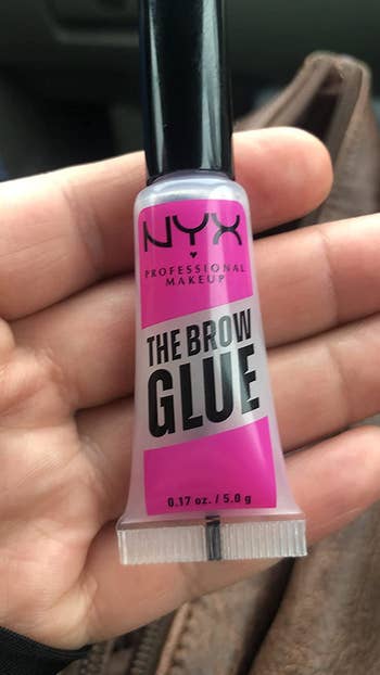 reviewer holding the glue in their hand, showing the size as big as a tube of lip gloss