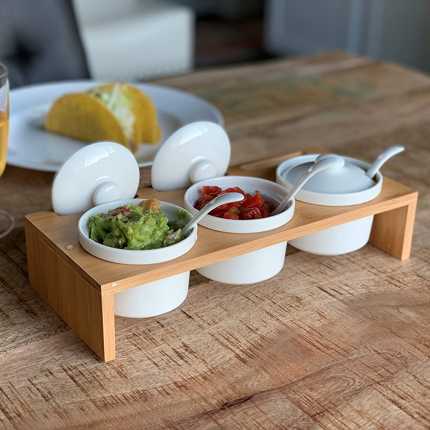 the wood server holding three ramekins with spoons and lids