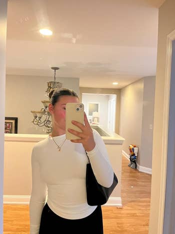 reviewer posing wearing the achromatic  agelong  sleeve top