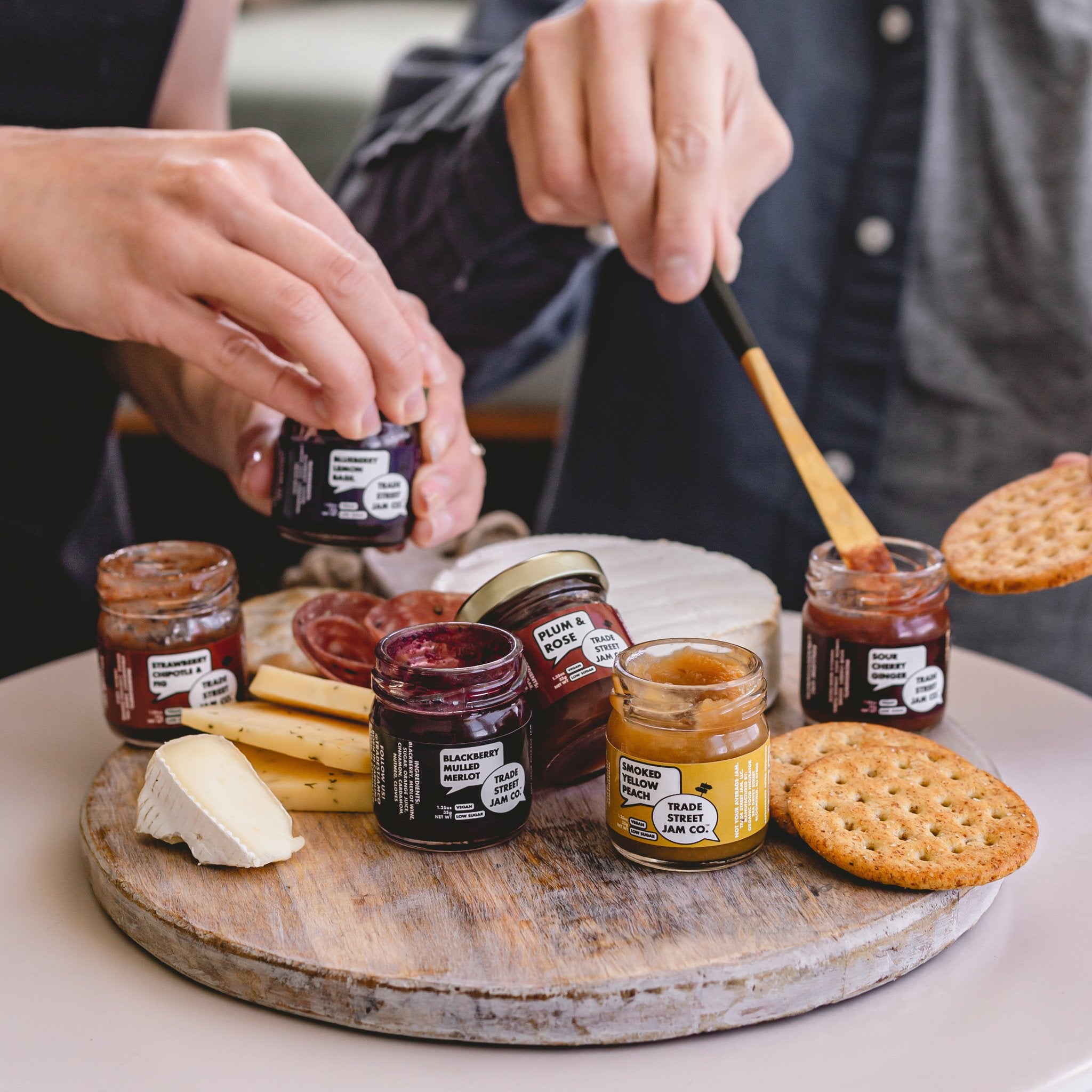 Models spreading the mini jam jars onto crackers and cheese