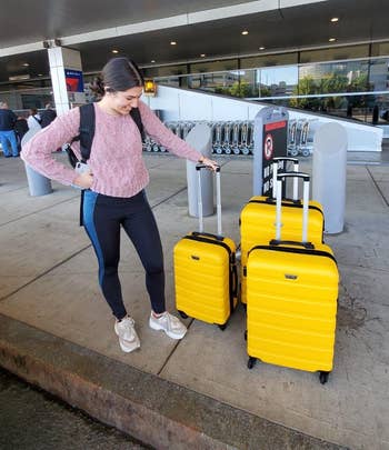 pic of reviewer with the three-piece luggage set in a yellow color