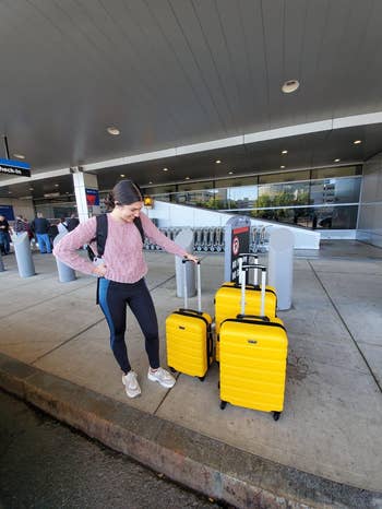 pic of reviewer with the three-piece luggage set in a yellow color