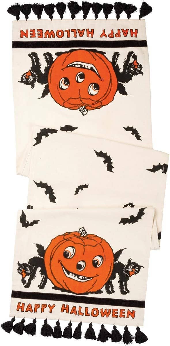 tasseled table runner with illustrated pumpkin and cat and the words happy halloween 