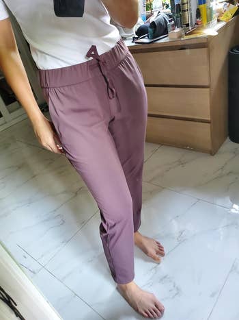 Person in white top and drawstring pants stands in room, focus on fit and style for shopping guide
