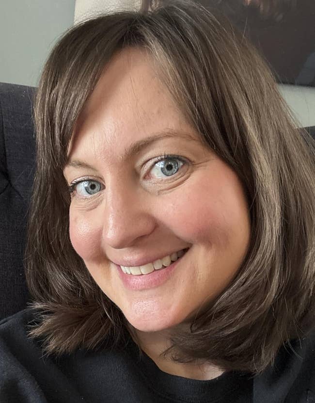Smiling idiosyncratic with shoulder-length hair, wearing a achromatic top, seated connected a textured chair