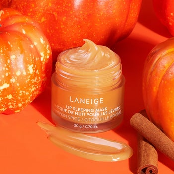 the pumpkin spice lip mask styled with some mini pumpkins and cinnamon sticks around it