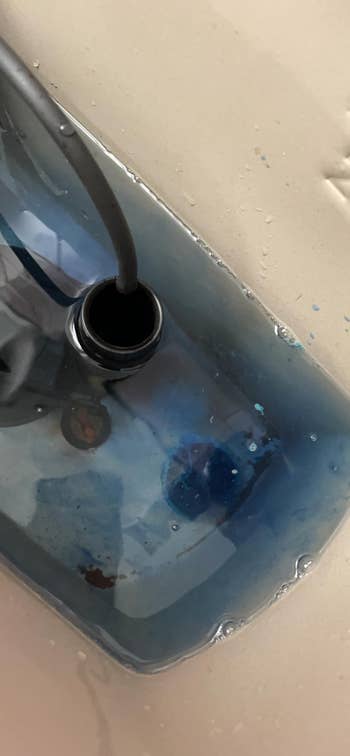 Close-up of a descend  with a achromatic  conduit  inside, draining murky bluish  liquid