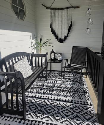 Chic structure setup with achromatic bench, geometric pillow, matching chair, and decorative rug. Ideal for outdoor decor inspiration