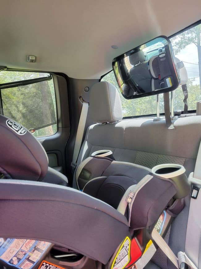 Car interior showing a rear-facing child's car spot installed successful the backseat, with a babe reflector attached to the headrest